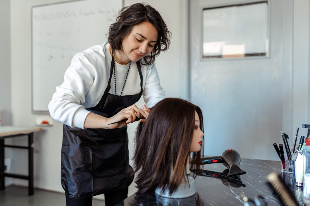 cosmetology student practicing hairstyling on mannequin head