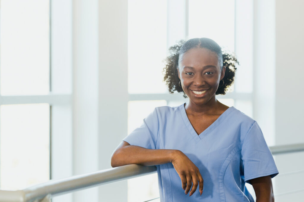 dental assistant standing near windows leaning on hand ail